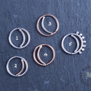 May include: Five silver and rose gold half-moon septum rings with numbers 1 through 5. The rings are on a dark gray background. Made in Argentium Silver.
