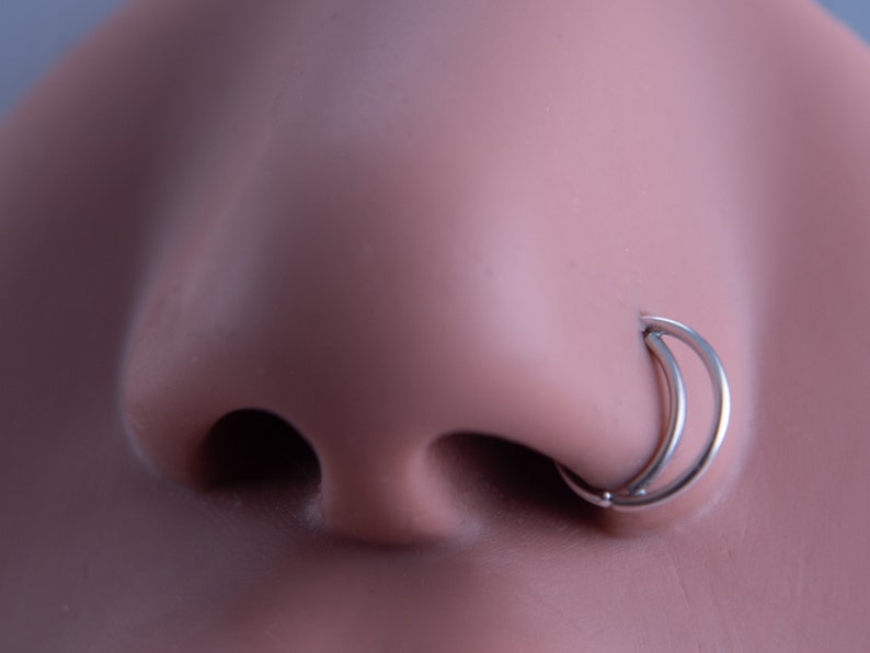 May include: A silver double hoop nose ring. The ring is made of two hoops that are connected together.