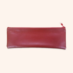 Op de afbeelding: Een rode etui met ritssluiting. De rechthoekige etui is gemaakt van een glad materiaal en heeft een bijpassende rode ritssluiting. De ritstrekker is ook rood. De etui is ontworpen om pennen, potloden en andere kleine items in op te bergen.