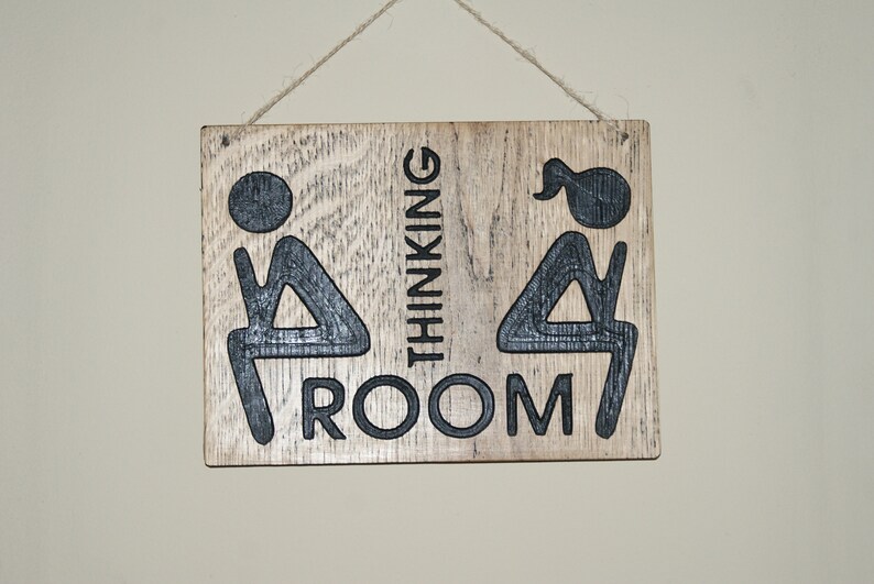 May include: A wooden sign with the text "Thinking Room" and two stick figures, one with a ponytail, sitting on a toilet.