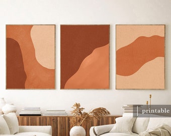 May include: Three abstract art prints with a minimalist design featuring organic shapes in shades of orange and brown. The prints are framed in a simple, modern style and are displayed on a white wall above a couch and coffee table.