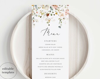 Puede incluir: Una tarjeta de menú blanca con un diseño floral de acuarela en la parte superior, con la palabra "Menú", y una lista de entrantes, platos principales y postres. El menú está en un plato blanco.