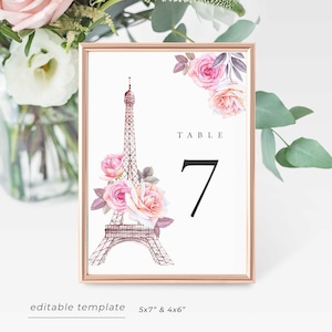May include: A printable table number template featuring a watercolor illustration of the Eiffel Tower and pink roses. The text "TABLE 7" is displayed on the template.