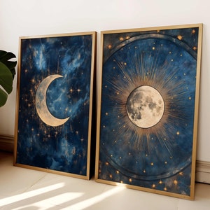 May include: Two framed prints with a celestial theme. The first print features a crescent moon with a gold outline against a dark blue background with gold stars. The second print features a full moon with a gold outline and rays of light emanating from it against a dark blue background with gold stars.
