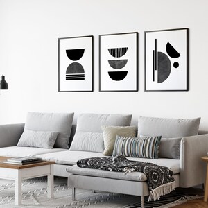 May include: A gray sectional sofa with three pillows, a black and white throw blanket, and a wooden coffee table in a living room with black and white abstract art prints on the wall.