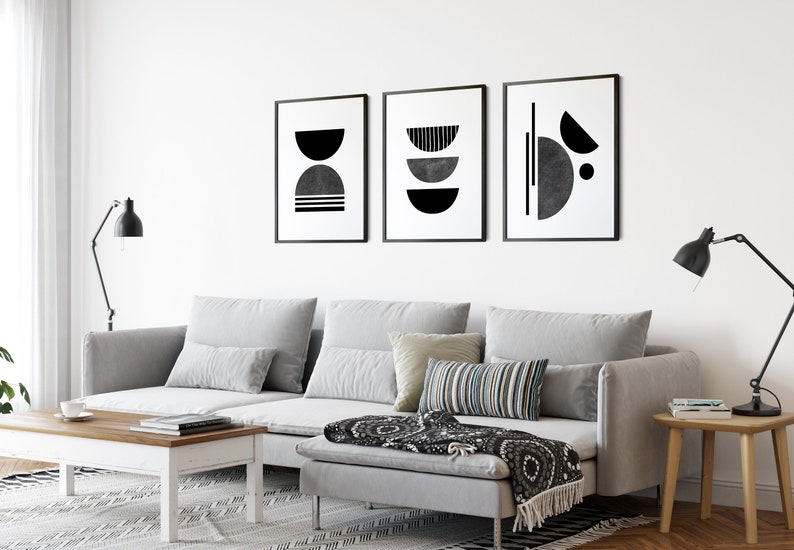 May include: A gray sectional sofa with three pillows, a black and white throw blanket, and a wooden coffee table in a living room with black and white abstract art prints on the wall.