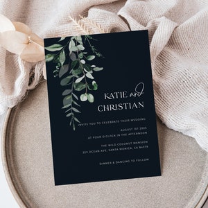 May include: A navy blue wedding invitation with elegant script and botanical accents. The invitation features the names "Katie and Christian" and event details, including the date, time, and location: The Wild Coconut Mansion in Santa Monica, CA.