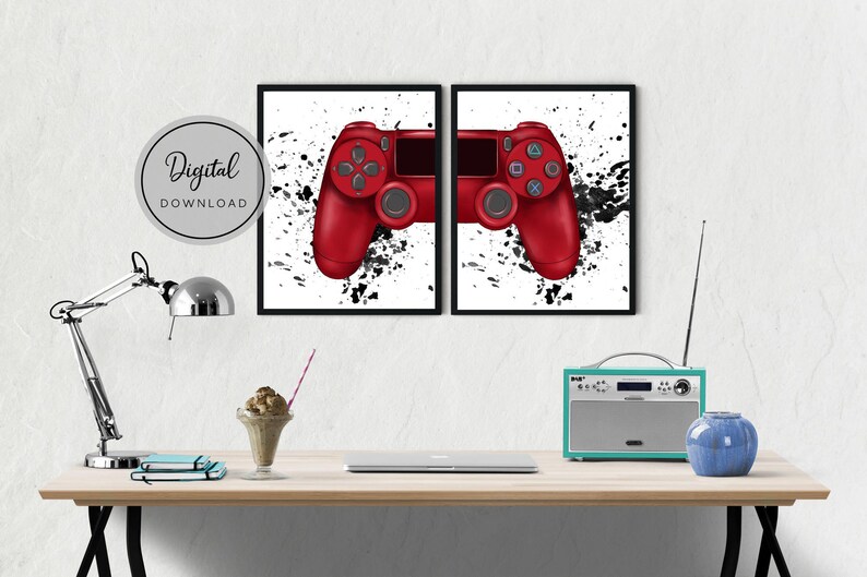 May include: Two framed prints featuring a red video game controller design with black splatter art on a white background. The prints are displayed on a white wall above a wooden desk. The text "Digital DOWNLOAD" is in a circle.