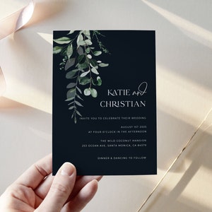 May include: A navy blue wedding invitation with the names "Katie and Christian" in white script. The invitation includes details for the wedding on August 1st, 2025, at The Wild Coconut Mansion. Greenery accents the top left corner.