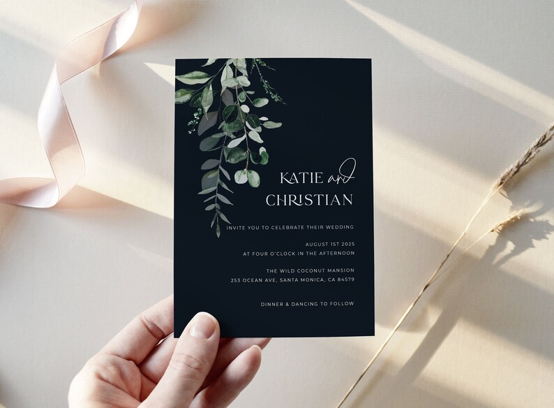 May include: A navy blue wedding invitation with the names "Katie and Christian" in white script. The invitation includes details for the wedding on August 1st, 2025, at The Wild Coconut Mansion. Greenery accents the top left corner.