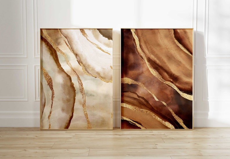 Peut inclure: Deux peintures abstraites avec des accents dor&eacute;s. La peinture de gauche a un fond brun clair avec des tourbillons blancs et dor&eacute;s. La peinture de droite a un fond brun fonc&eacute; avec des tourbillons dor&eacute;s.