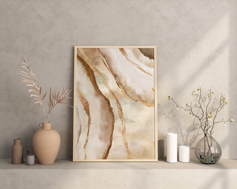 Peut inclure: Une impression abstraite encadr&eacute;e avec un fond beige et brun et des accents dor&eacute;s. L'impression pr&eacute;sente un design marbr&eacute; tourbillonnant.