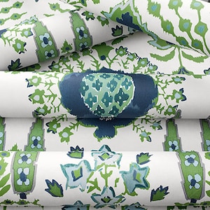 K&ouml;nnte beinhalten: Nahaufnahme eines wei&szlig;en Stoffes mit einem sich wiederholenden Muster aus gr&uuml;nen und blauen floralen Designs. Der Stoff ist in mehreren Schichten gefaltet, wodurch die komplizierten Details des Musters hervorgehoben werden.