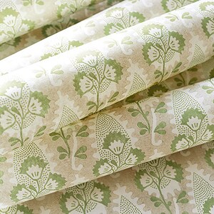 May include: Close-up of a beige and green patterned fabric with a floral design. The fabric has a subtle texture and a soft, muted color palette.