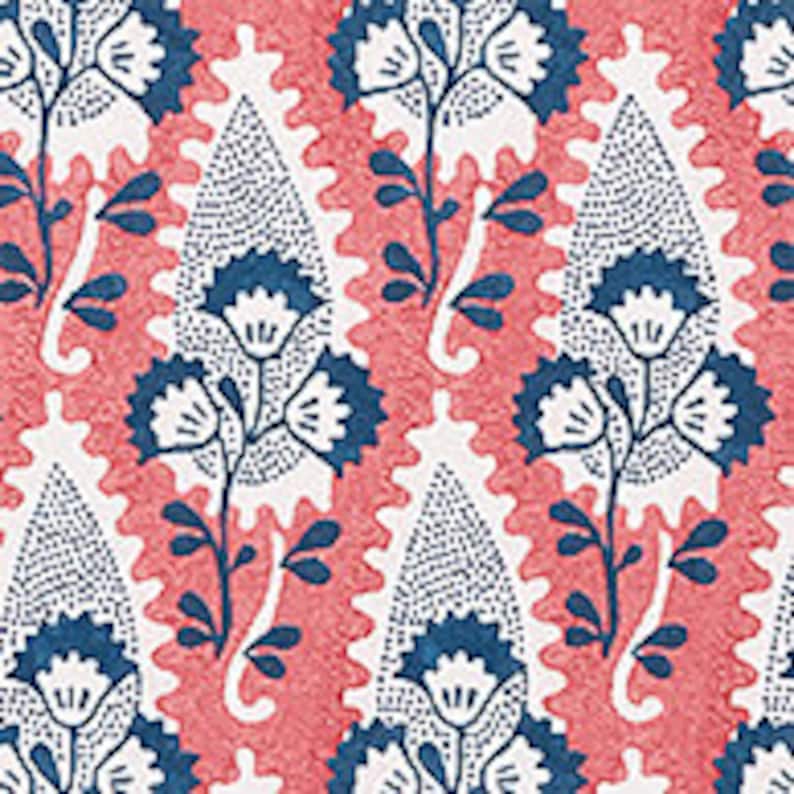 May include: A repeating pattern of blue and pink paisley shapes with white floral designs. The paisley shapes are outlined in blue and filled with a white dotted pattern. The floral designs are stylized and have white petals and blue stems.