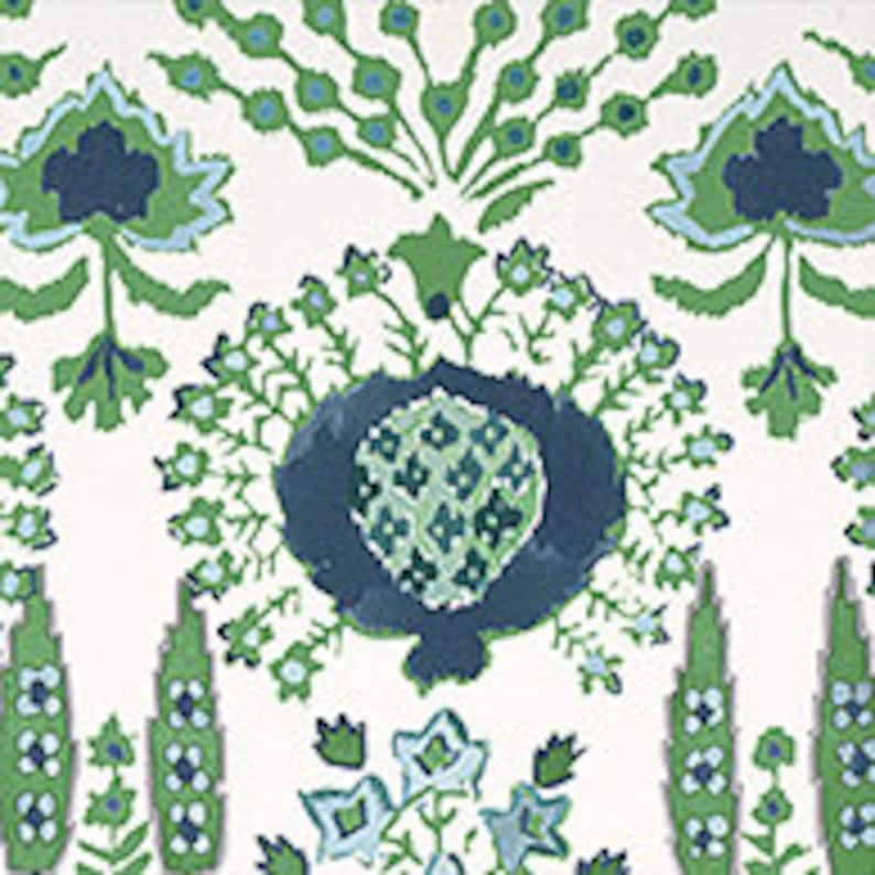 K&ouml;nnte beinhalten: Ein wei&szlig;er Hintergrund mit einem gr&uuml;nen und blauen Blumenmuster. Das Muster zeigt stilisierte Blumen, Bl&auml;tter und ein zentrales Motiv, das einem stilisierten Herzen &auml;hnelt.