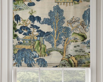 May include: A white window blind with a blue and green Asian-inspired print featuring trees, a bridge, and a pagoda. The blind is partially rolled up, revealing a view of a grassy area through the window.