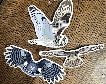 May include: Three black and white owl stickers with detailed patterns. The owls are in different poses, with one flying, one looking straight ahead, and one looking to the side.