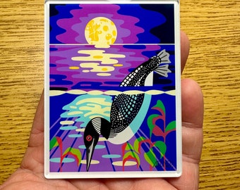 Könnte beinhalten: Ein rechteckiger Acrylmagnet mit einer grafischen Illustration eines Eistauchers, der in blaues Wasser eintaucht. Die Szene zeigt einen gelben Vollmond, der sich über dem Wasser in einem violetten und blauen Himmel spiegelt, mit grünen Wasserpflanzen.