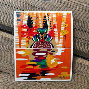 May include: A colorful art print featuring a stylized duck in a forest scene. The artwork uses geometric shapes and vibrant colors, including orange, green, and brown. The duck is reflected in the water below. The artist's signature is in the bottom right corner.