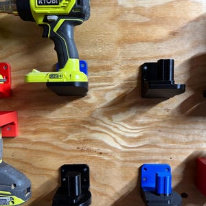 May include: A yellow and black Ryobi drill with a black and blue wall mount. The drill is labeled "RYOBI ONE+". There are three other wall mounts, one black and two blue, on a wood panel.