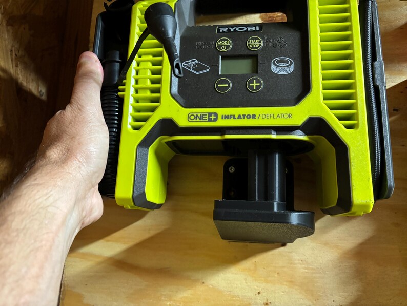 May include: A green and black Ryobi One+ Inflator/Deflator with a digital display and a black hose. The device is plugged into a black power source.