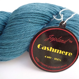 May include: A teal blue skein of 4-ply cashmere yarn with a black and red label that reads "Jojolands TM Cashmere 4 ply - 100% http://www.jojolands.com"