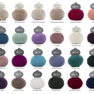 May include: A collection of 18 skeins of yarn in various colors, including white, beige, brown, green, purple, pink, blue, teal, red, and gray. Each skein is labeled with the yarn's color name and number.