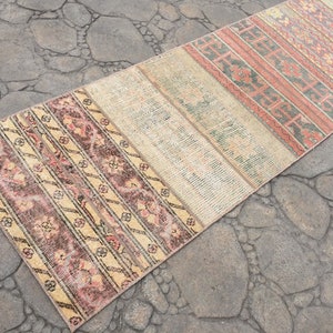 May include: A long, narrow rug with a patchwork design. The rug is made of different fabrics and colors, including beige, pink, and brown. The rug has a vintage look and would be perfect for adding a touch of bohemian style to a room.