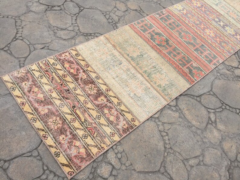 May include: A long, narrow rug with a patchwork design. The rug is made of different fabrics and colors, including beige, pink, and brown. The rug has a vintage look and would be perfect for adding a touch of bohemian style to a room.