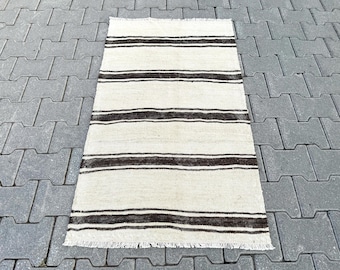 May include: A white and brown striped rug with a fringe border. The rug is made of wool and has a traditional design.