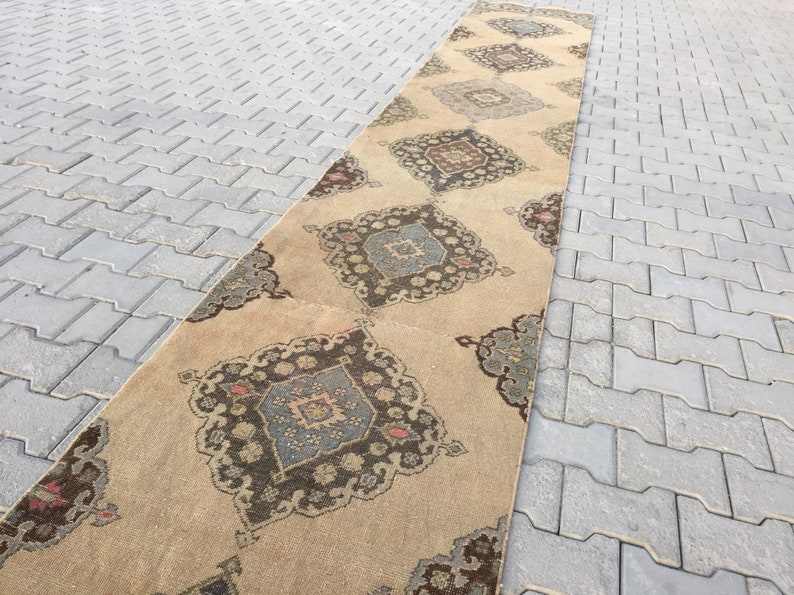 Pu&ograve; includere: Un tappeto runner beige con un designo persiano tradizionale che presenta motivi intricati in tonalit&agrave; di marrone, blu e rosso.
