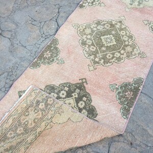 May include: A pink and green vintage rug with a floral pattern. The rug is folded in half and has a distressed look.