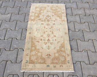 May include: A vintage rug with a beige background and a brown floral pattern. The rug has a fringe border and is laid out on a gray concrete surface.
