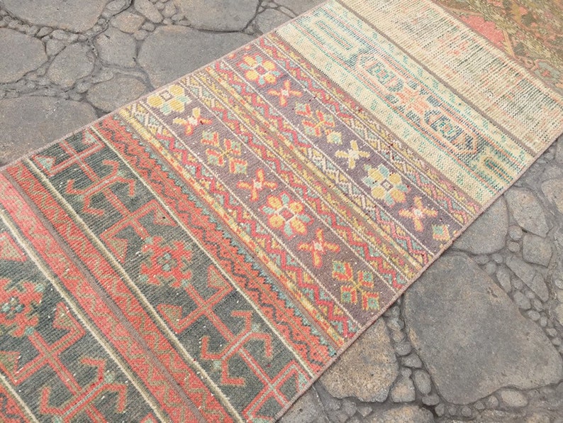May include: A colorful vintage rug with a geometric pattern in shades of red, orange, yellow, green, and blue. The rug is made of woven fabric and has a distressed look.