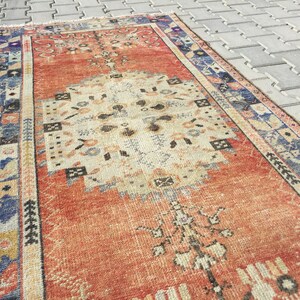 May include: A vintage, hand-woven rug with a red, cream, and blue color scheme. The rug has a traditional Persian design with intricate floral patterns and geometric shapes.