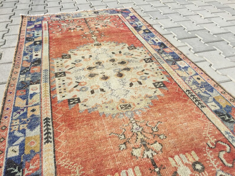 May include: A vintage, hand-woven rug with a red, cream, and blue color scheme. The rug has a traditional Persian design with intricate floral patterns and geometric shapes.
