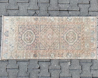 May include: A light beige and pink vintage rug with a geometric pattern. The rug has a fringed edge and is made of wool.
