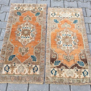 Può includere: Due tappeti turchi vintage da corridore con un motivo floreale tradizionale in tonalità di arancione, marrone, beige e blu. I tappeti hanno un bordo con frange.