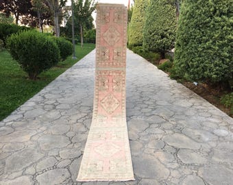 Puede incluir: Una alfombra de pasillo rosa y crema con un patrón geométrico. La alfombra está colocada en un camino de piedra.