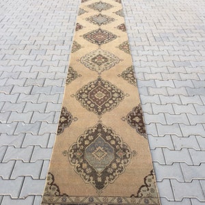 Pu&ograve; includere: Un tappeto da corridoio lungo e beige con un design persiano tradizionale. Il tappeto presenta motivi intricati in tonalit&agrave; di marrone, blu e rosso.