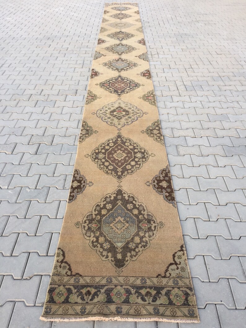 Pu&ograve; includere: Un tappeto da corridoio lungo e beige con un design persiano tradizionale. Il tappeto presenta motivi intricati in tonalit&agrave; di marrone, blu e rosso.