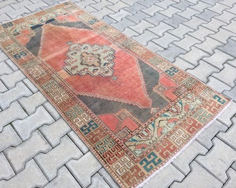 Puede incluir: Una alfombra turca vintage de corredor con un patrón geométrico rojo, verde y azul. La alfombra tiene un aspecto descolorido y desgastado y está hecha de lana.