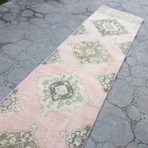 May include: A pink and beige runner rug with a geometric pattern. The rug has a faded, vintage look.