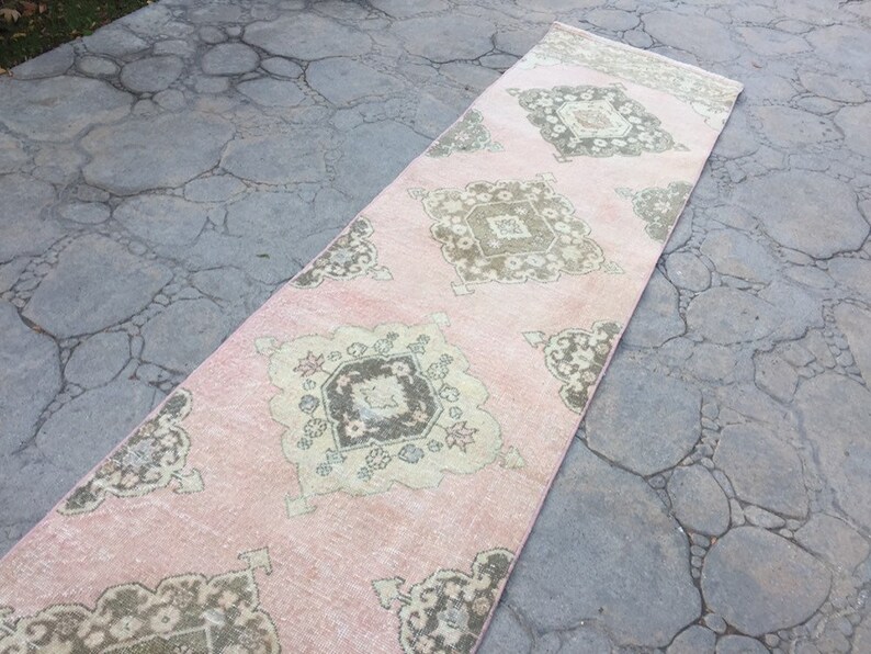 May include: A pink and beige runner rug with a geometric pattern. The rug has a faded, vintage look.