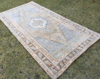 May include: A light blue and beige vintage rug with a geometric pattern. The rug has a faded look and a distressed texture.