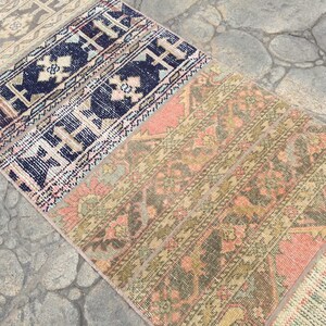 May include: A multi-colored vintage rug with a geometric pattern. The rug is made up of several different pieces of fabric sewn together. The rug is a mix of pink, blue, green, and brown.