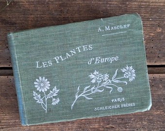 May include: A green hardcover book titled Les Plantes d'Europe by A. Masclef, published by Schleicher Frères in Paris. The cover features white line illustrations of two flowering plants, with the title and author printed in white text.