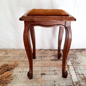 Peut inclure: Petit tabouret en bois de couleur marron fonc&eacute; avec un coussin marron. Les pieds sont incurv&eacute;s et sculpt&eacute;s. Le tabouret est de style ancien. Dimensions: environ 40 cm de hauteur, 30 cm de largeur et de profondeur.