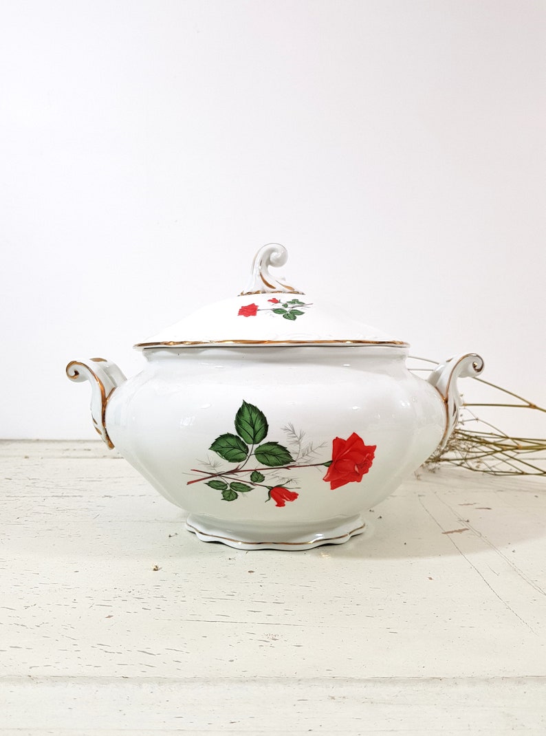 May include: White porcelain sugar bowl with a lid and gold trim. The bowl has a floral design with red roses and green leaves.